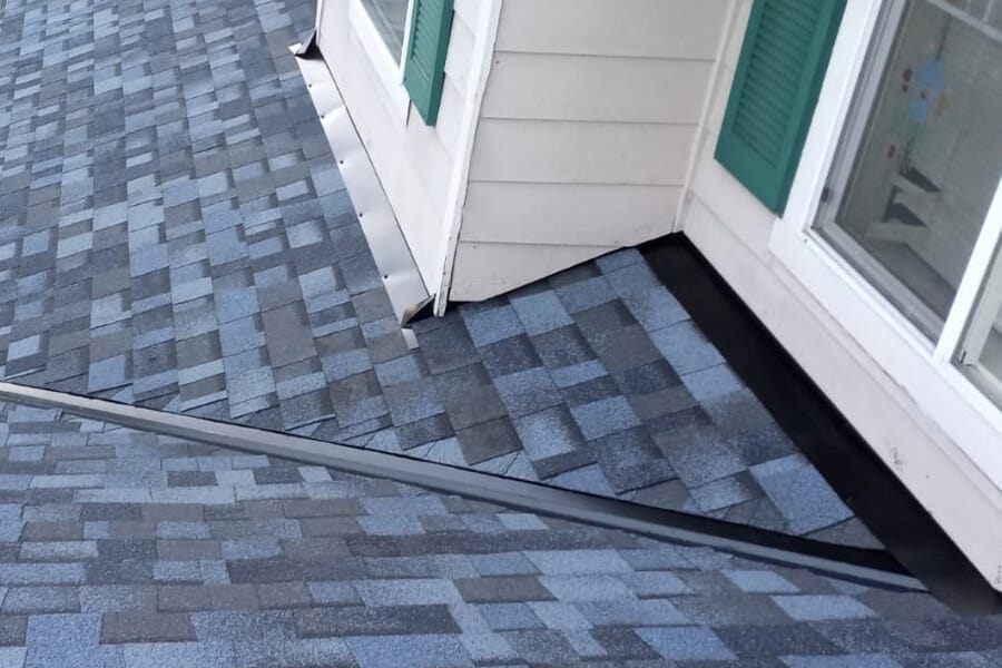 Shingles running into the sidewall of a bay window, with metal flashing along the joint.